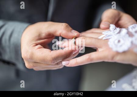 Groom putting the wedding ring on bride finger close up. Stock Photo