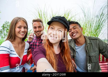 Multicultural guys and girls taking selfie outdoors - Happy friendship concept on young multiethnic people having fun day together Stock Photo