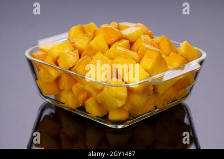 Ripe Mango cubes or cut piece arranged in a glass square container with black color background. Stock Photo