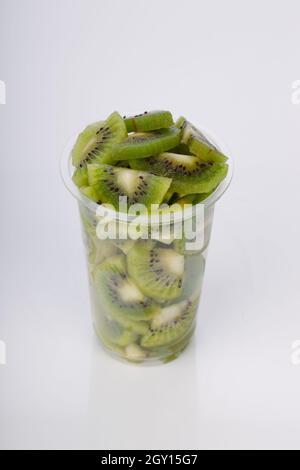 Kiwi fruit slices or cut piece arranged in a transparent glass with white color background. Stock Photo