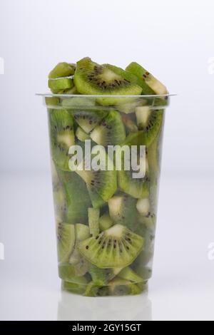 Kiwi fruit slices or cut piece arranged in a transparent glass with white color background. Stock Photo