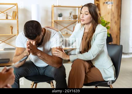 Two young people, married couple sitting in psychologist's office. Look depressed, angry. despaired Stock Photo