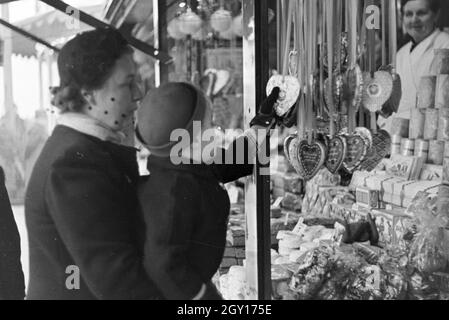 Eine Mutter mit ihrem kleinen Sohn auf dem Weihnachtsmarkt, Deutsches Reich 1930er Jahre. A woman with her little son on the Christmas market, Germany 1930s. Stock Photo