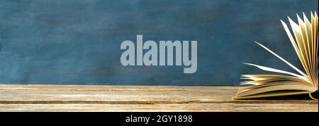 Open book, hardback book on wooden table on dark blue background. Back to school,education,reading. Copy space Stock Photo