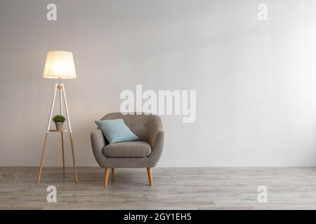 https://l450v.alamy.com/450v/2gy1eh5/retro-armchair-with-blue-pillow-plant-in-pot-glowing-lamp-on-floor-in-evening-2gy1eh5.jpg