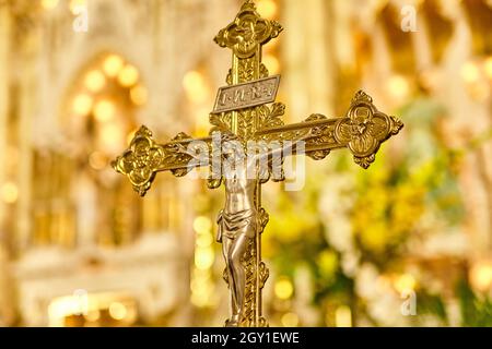 Close-up of an ornately decorated crucifix with the back wall of the sanctuary in the background Stock Photo