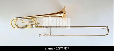 Trombone with transposer mounted on a white table. Top view. Horizontal composition. Stock Photo