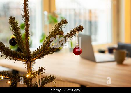 Working at home during the holidays. Christmas tree with decorations. In the background is laptop on wooden table. Photo taken in Sweden. Stock Photo