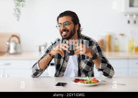 Smiling arab guy having breakfast, looking at copy space Stock Photo