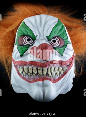 Adult Orange-Haired Clown Mask Isolated Against Black Background Stock Photo