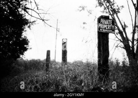 A series of sign posts, the closest one reading Private Property, in black and white Stock Photo