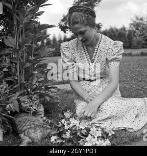 Eine junge Frau spielt im Garten mit einer Katze, Deutschland 1930er Jahre. A young woman playing with a cat in the garden, Germany 1930s. Stock Photo