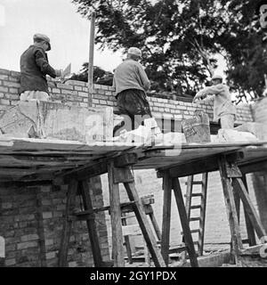 Maurer bei der Arbeit auf einer Baustelle eines Hauses, Deutschland 1930er Jahre. Brick layers at work on a new house, Germany 1930s. Stock Photo