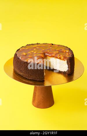 Sliced Birthday cake on the wooden cake stand. Cheesecake in a chocolate crust. Yellow background. Copy space. Food photography for recipe. Stock Photo