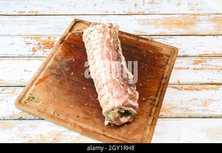 Preparation of a porchetta with a mixture of aromatic herbs placed on a piece of fresh pork belly open in the thickness Stock Photo