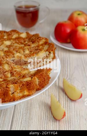 Apple pie on a plate on a wooden table against a background of red apples. Stock Photo
