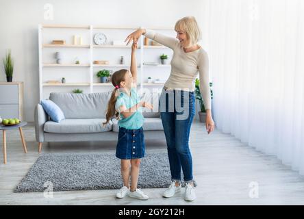 Cheerful grandmother dancing to music with little granddaughter Stock Photo
