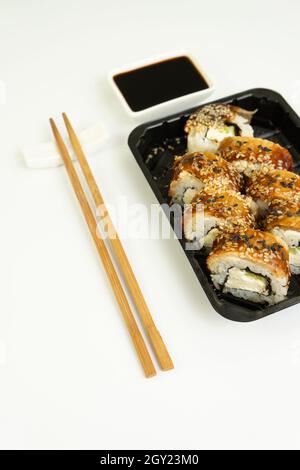 Sushi delivery box on a white background. Japanese menu in black transport box with chopsticks Stock Photo