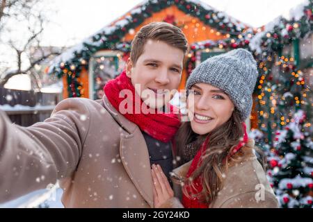 Cheerful lovers taking selfie while spending snowy day outside Stock Photo