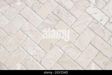 Gray white brick sidewall pavers. Stones laid down on ground pavement walkway. Building texture flat wall. Stock Photo