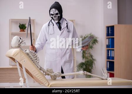 Devil doctor radiologist examining skeleton patient at the hospital Stock Photo