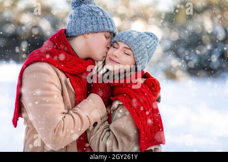 Loving man kissing his pretty girlfriend while enjoyng snowy weekend Stock Photo
