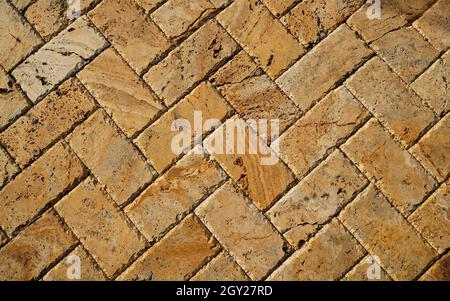 Yellow brown stone pavers background. Neutral texture of a flat brick wall close-up. Stock Photo