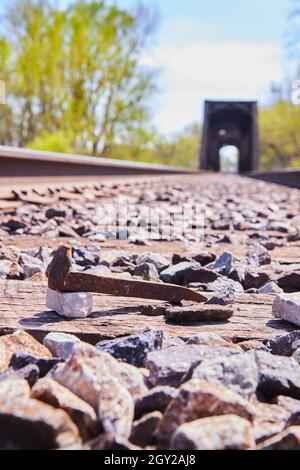 Railroad spike on train tracks with bridge in background Stock Photo