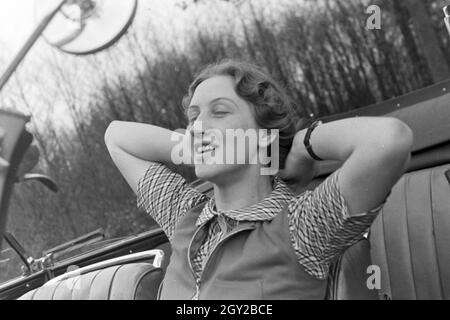 Eine junge Frau  entspannt sich in ihrem Cabrios, Deutschland 1930er Jahre. A young woman relaxing in her convertible, Germany 1930s. Stock Photo