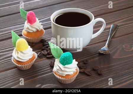 Cup of coffee and small colorful cakes on brown wooden table Stock Photo