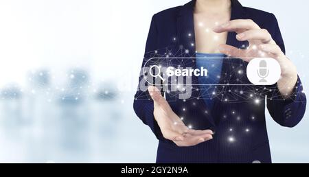 Searching Internet Data. Web Browsing Concept. Two hand holding virtual holographic search data icon with light blurred background. Minimal blank sear Stock Photo