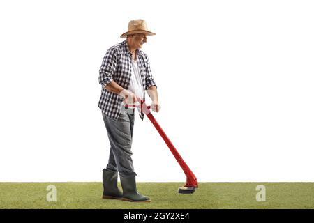 Full length shot of a mature man trimming grass with a grass trimmer isolated on white background Stock Photo