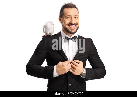 Joyful young man in suit and bow-tie smiling and standing with a white dove on his shoulder isolated on white background Stock Photo