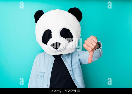 Funny man in panda mask with thumbs down gesture Stock Photo