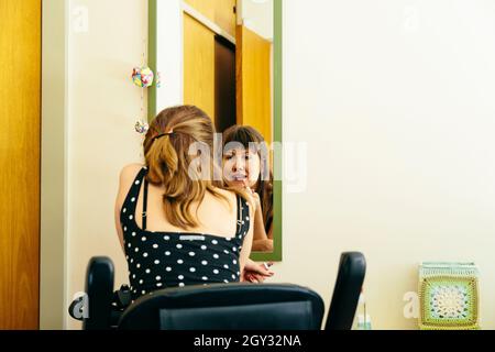 Woman in a wheelchair scooter putting on makeup in front of a mirror. Copy space. Stock Photo