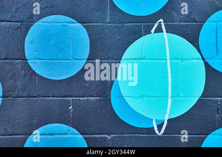 Black cement painted wall with blue spots and teal planet Stock Photo