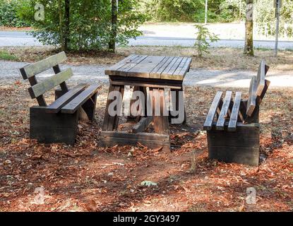 Outdoor old wooden table and benches in the autumn park under sunbeams Stock Photo
