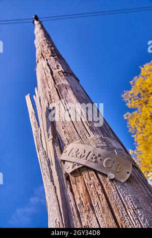 Texture of wood telephone pole with metal plate against blue sky Stock Photo