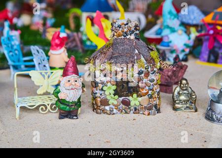 Miniature gnome, buddha, and pebble house in sand Stock Photo