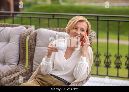 Cheerful blonde female calling on her cellphone on the terrace Stock Photo
