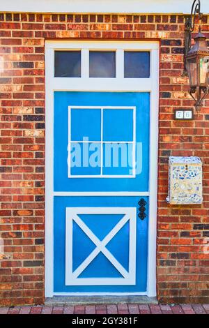 Bright blue and white dutch-style door on red brick Stock Photo