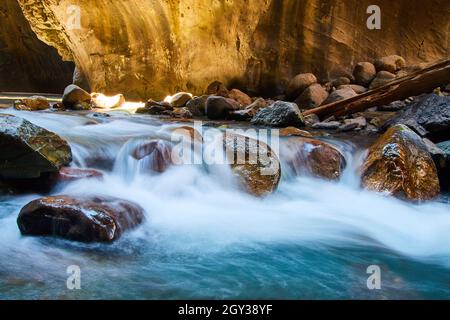 Boulders with water flowing over in deep golden canyon Stock Photo