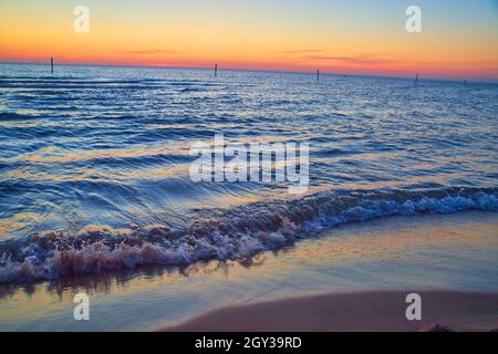 Beach on lake with waves of water and sunset colors on horizon Stock Photo