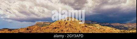 Panorama of large golden brown mountain range against ominous and dark storm clouds Stock Photo