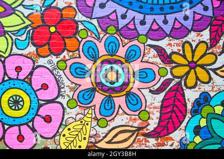 Brick wall straight on covered in colorful flower artwork Stock Photo