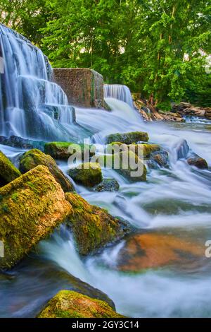 Waterfalls crashing around small algae-covered rocks Stock Photo