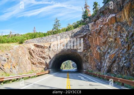 View in center of road of tunnel through the mountains with stone wall Stock Photo