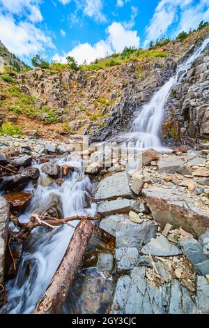 Waterfall down angled slope of gray rocks in the mountains Stock Photo