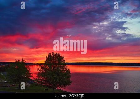 Lake with trees during sunset with vibrant colors of purple, red and orange Stock Photo