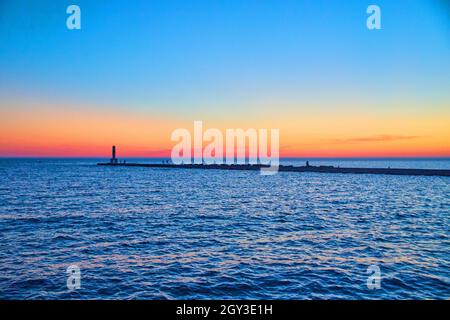 Beautiful sunset or sunrise on lake with pier silhouette and colorful sky of red, orange, and blue Stock Photo